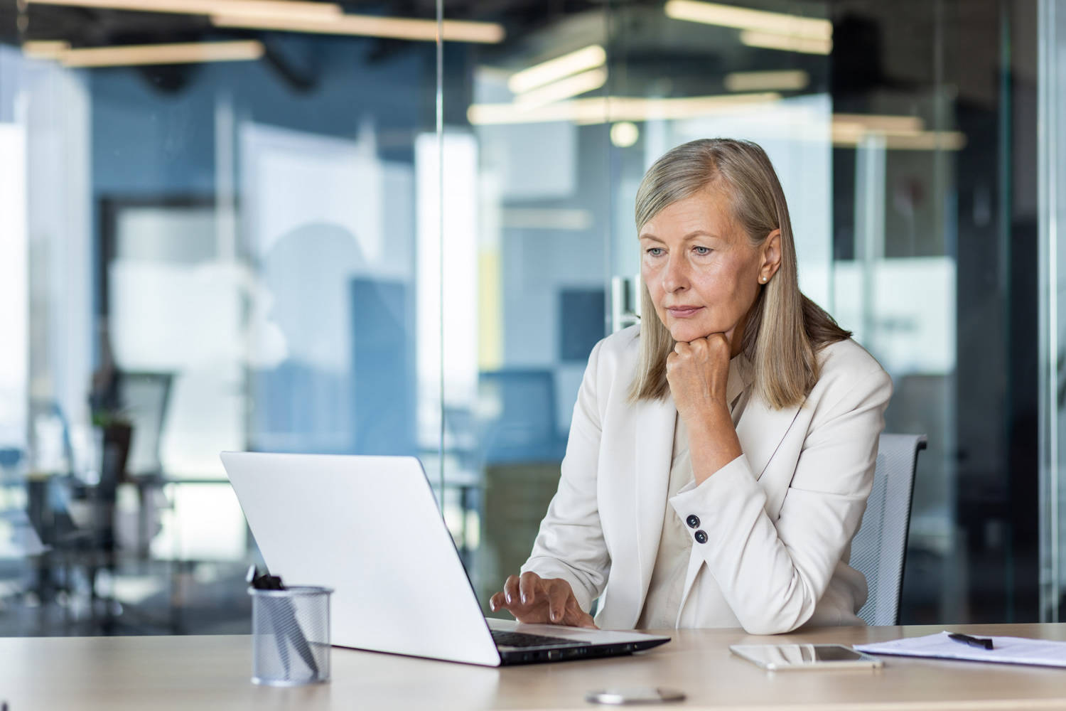 Serious thinking businesswoman working inside office with notebook