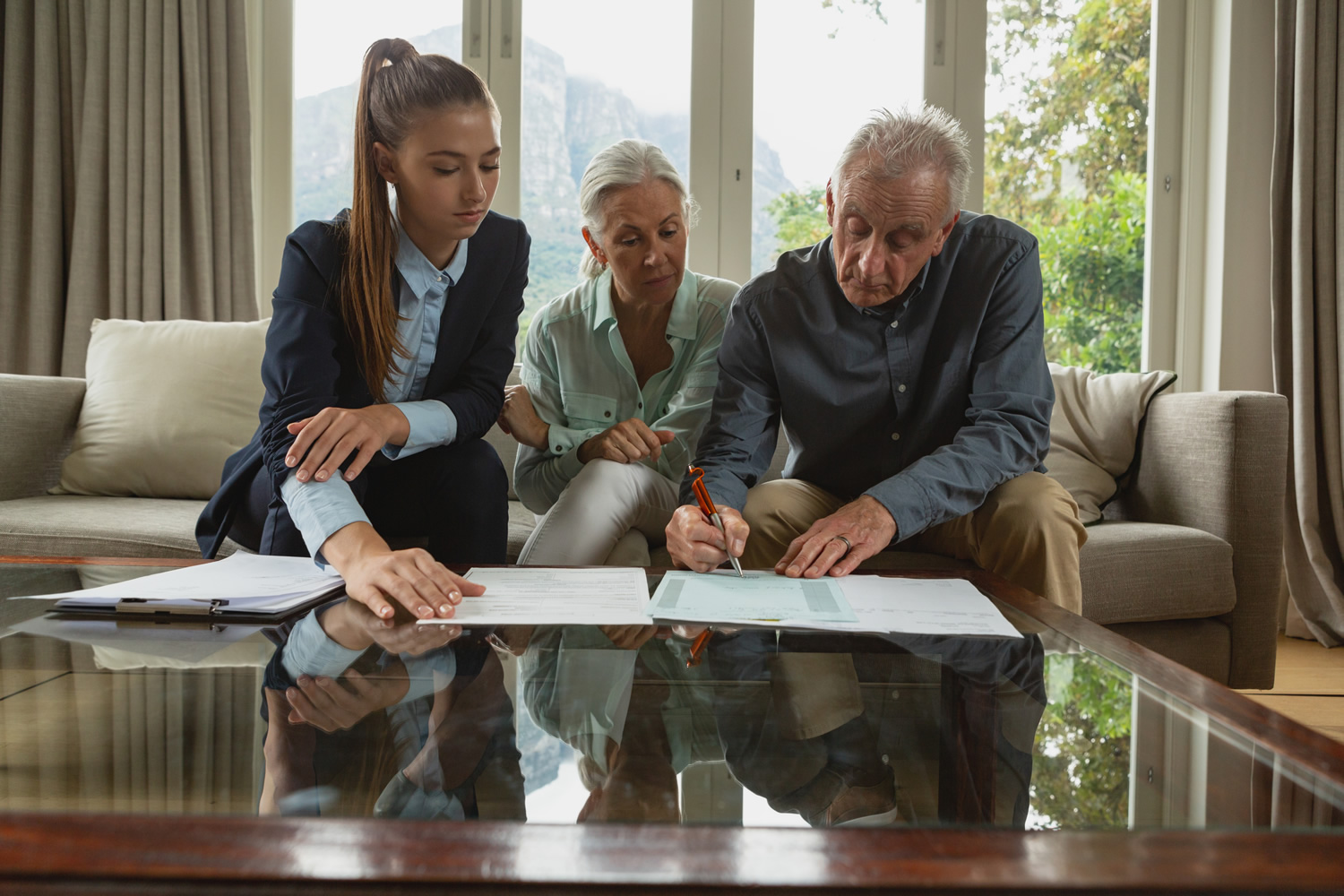 Active senior couple signing an agreement with real estate agent over documents in living room