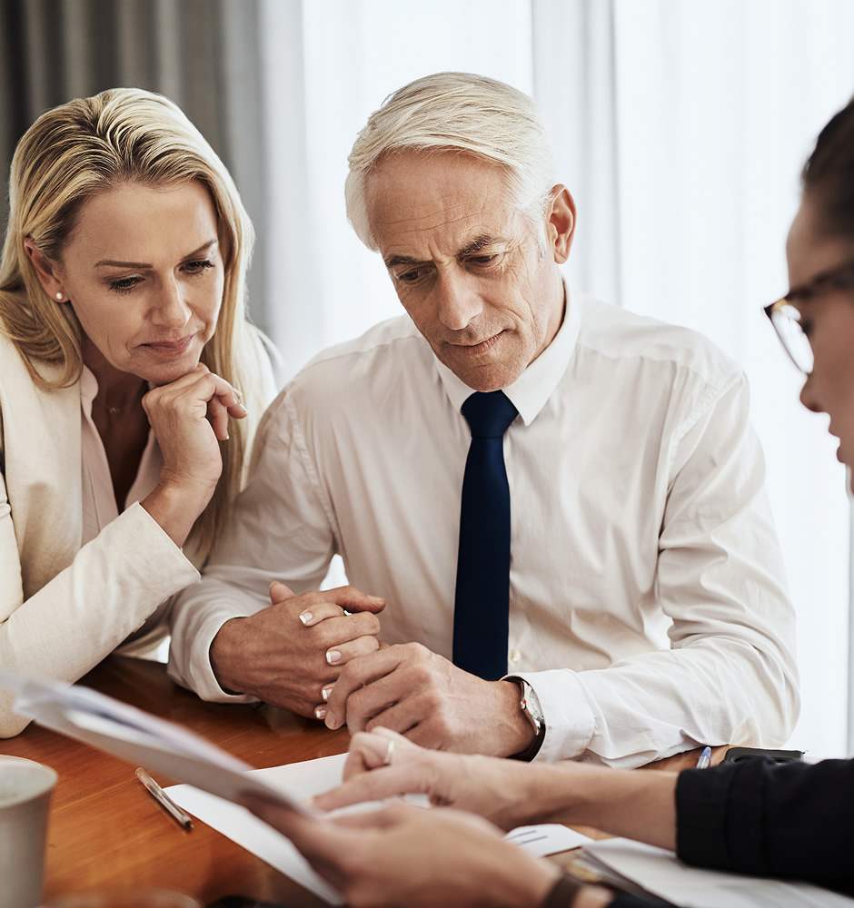 There is some interesting material here shot of a focused mature couple negotiating with a architect over house plans around a table inside of a building during the day